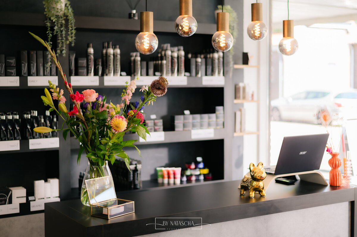 De balie van Haarstudio Heesch met bloemen in de vaas en een laptop