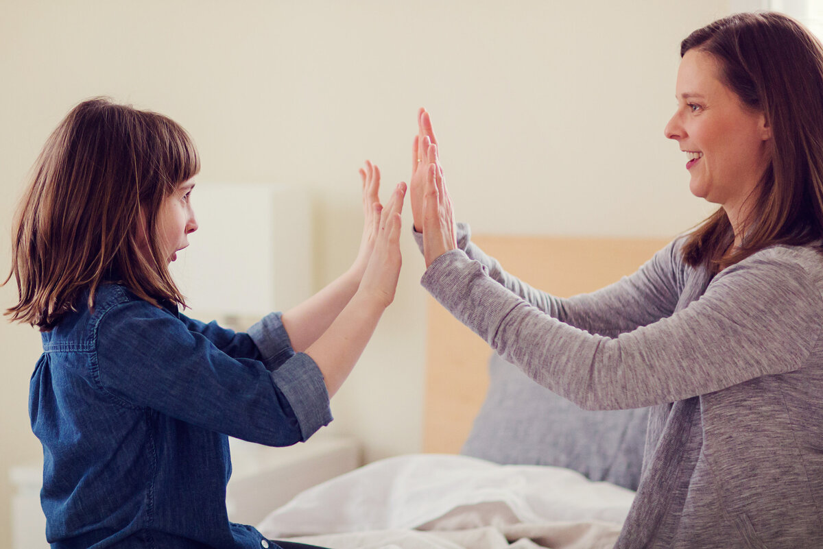 Mom and daughter are giving high fives to each other.