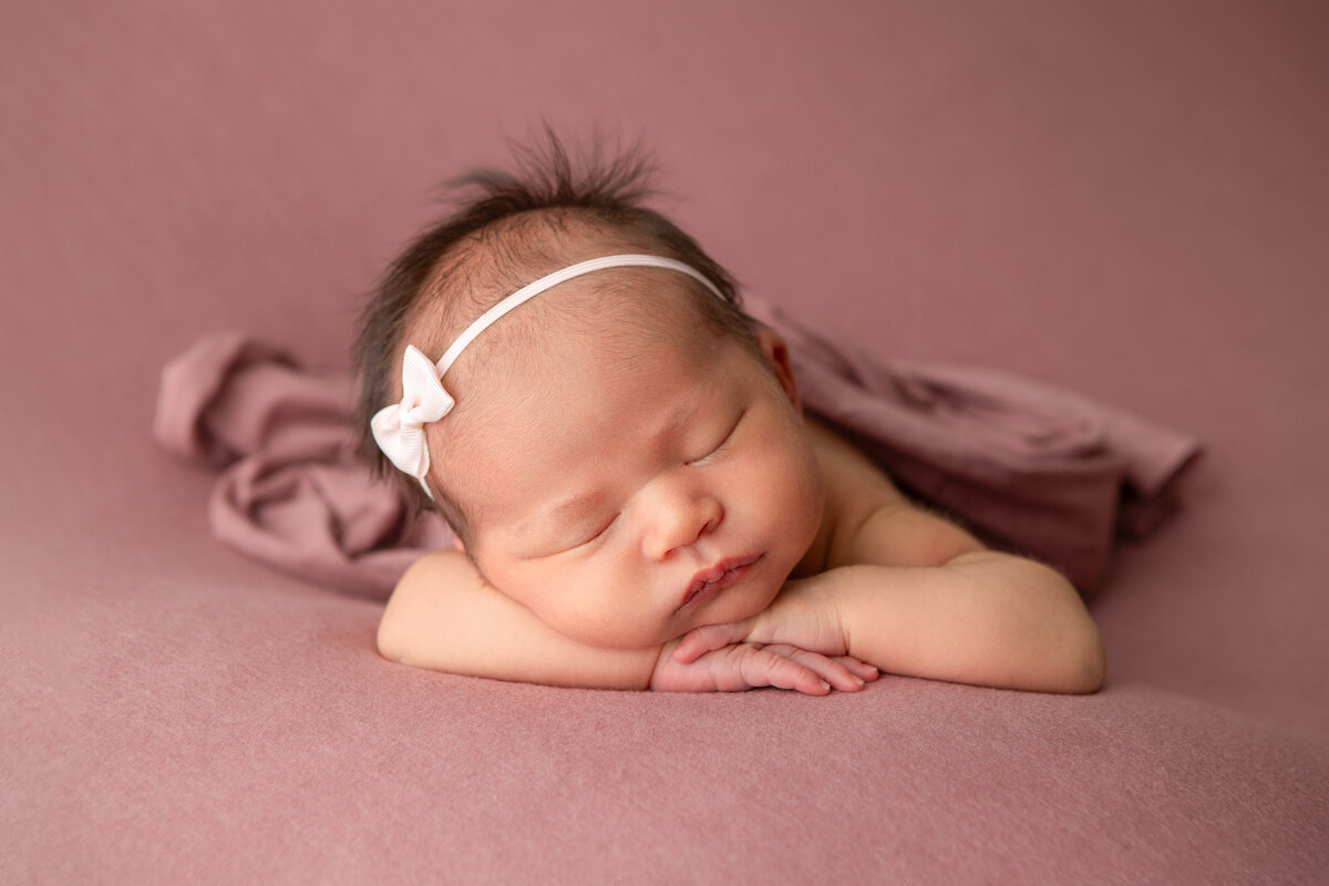 Studio chin on hands table newborn pose on a mauve backdrop