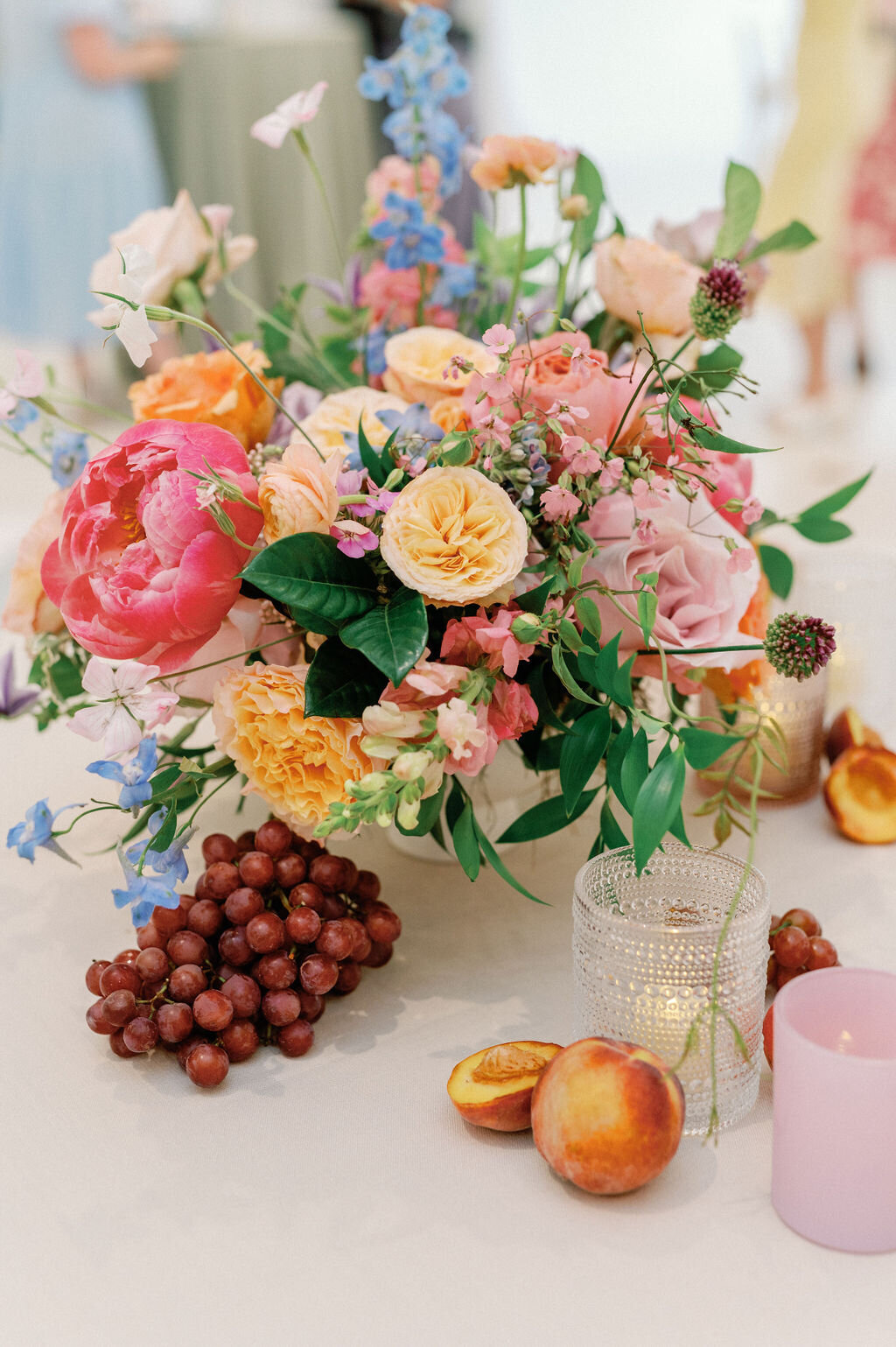 Fun and bright wedding florals for summer wedding reception. Styled fruit and colorful candles on wedding reception tables. Fun summer color palette in peach, coral, lavender, and light blue. Bright and cheerful floral design for Tennessee wedding. Design by Rosemary & Finch Floral Design in Nashville, TN. 