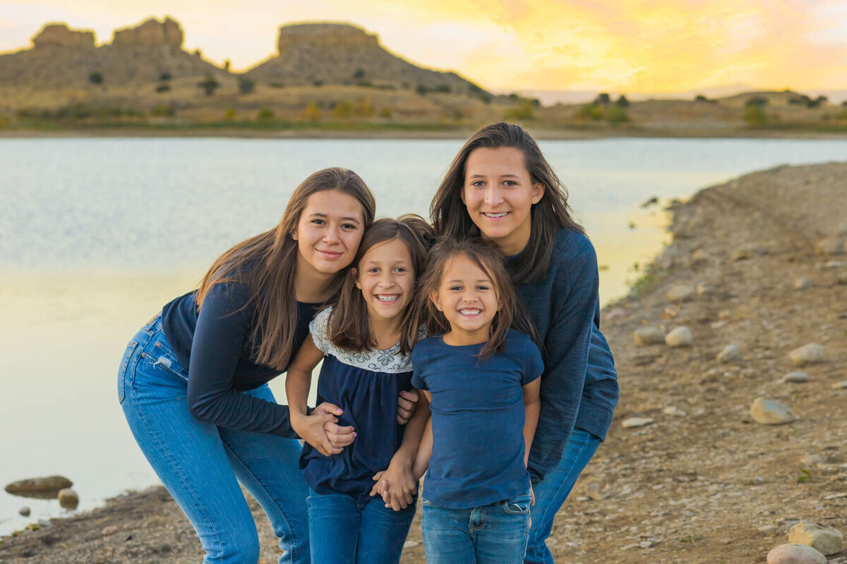 four sisters standing together smiling on a beach near Lake Pueblo