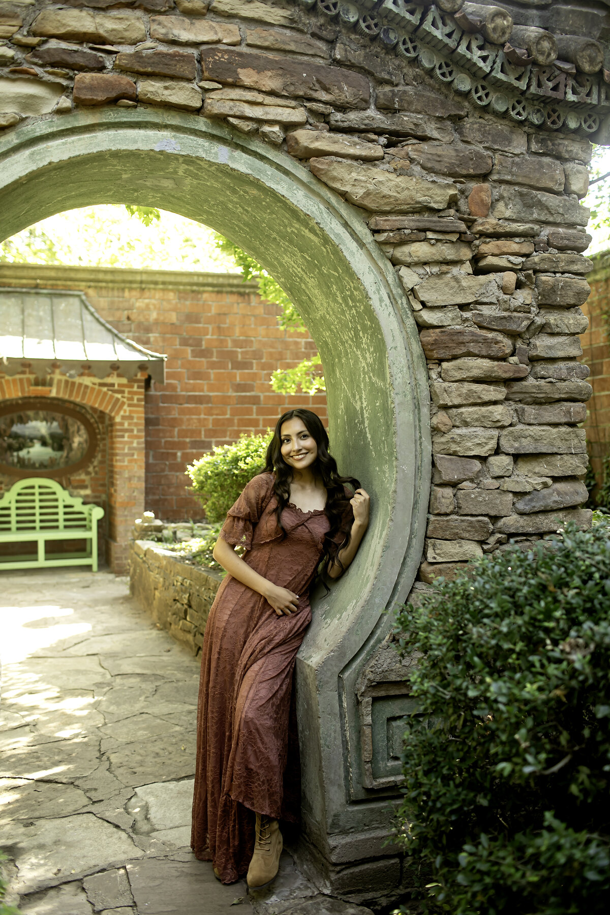 A high school senior in a delicate dress, framed by the exquisite greenery and flowers of Chandor Gardens, creating a peaceful and timeless photoshoot moment