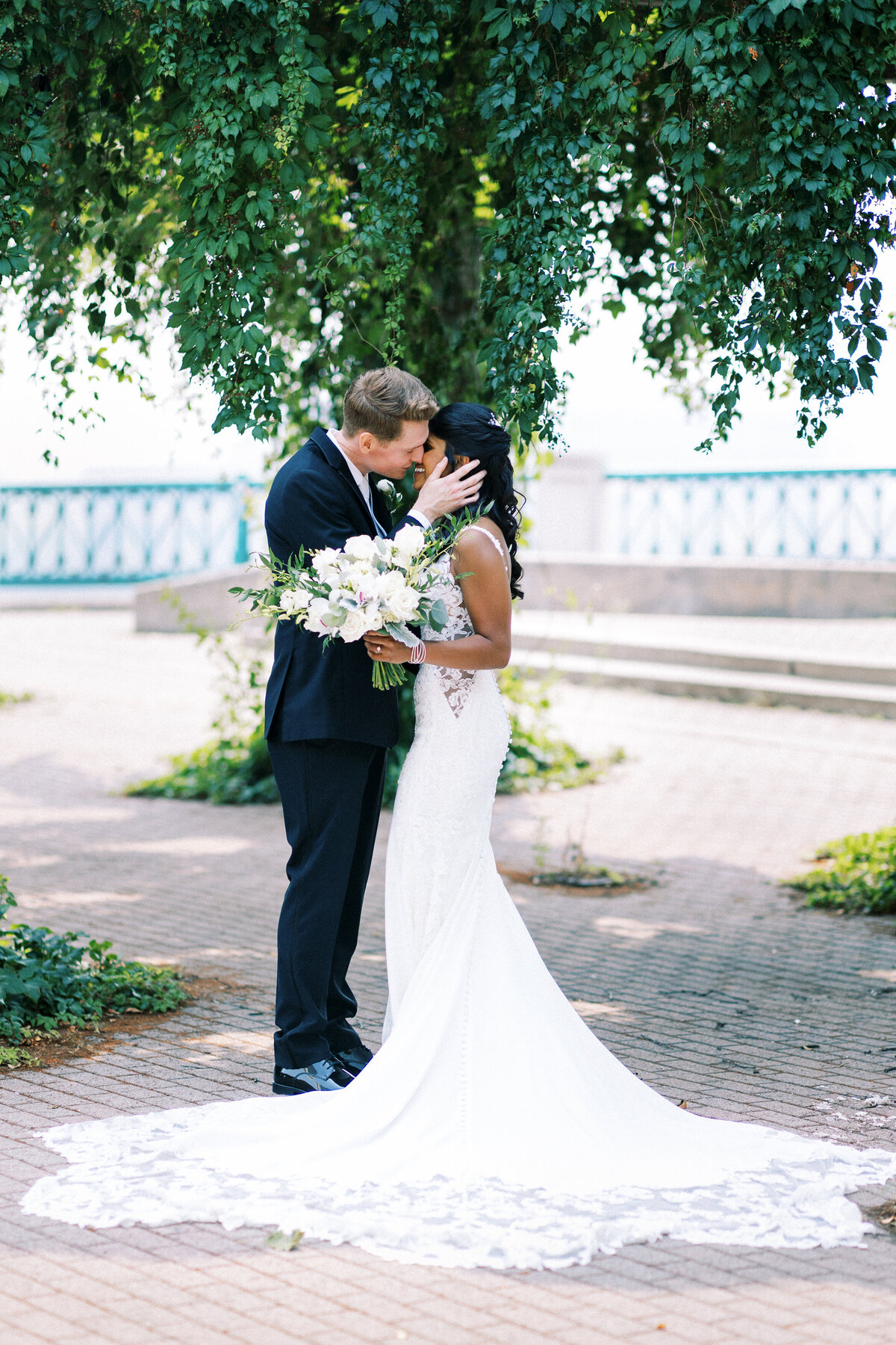 Groom holding brides face while kissing her