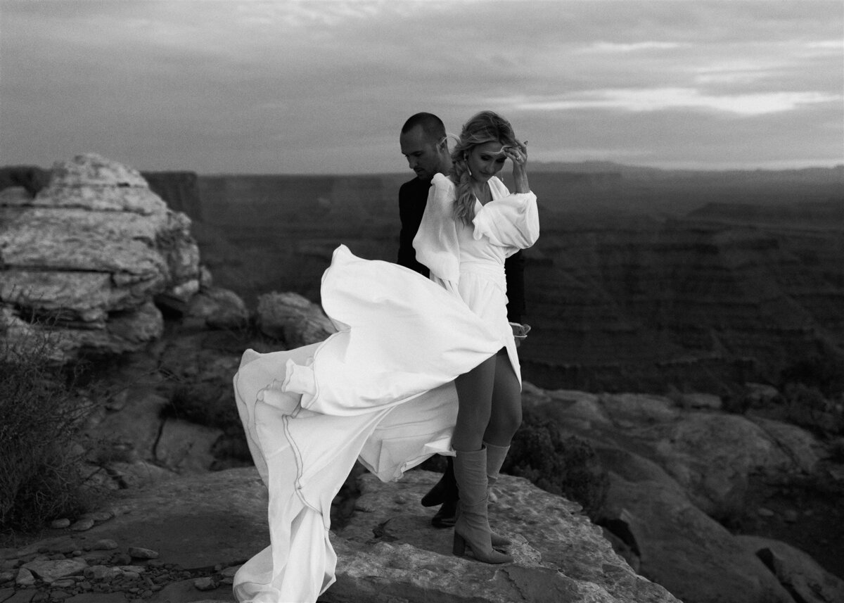 newlyweds standing in front of canyon together in moab, utal