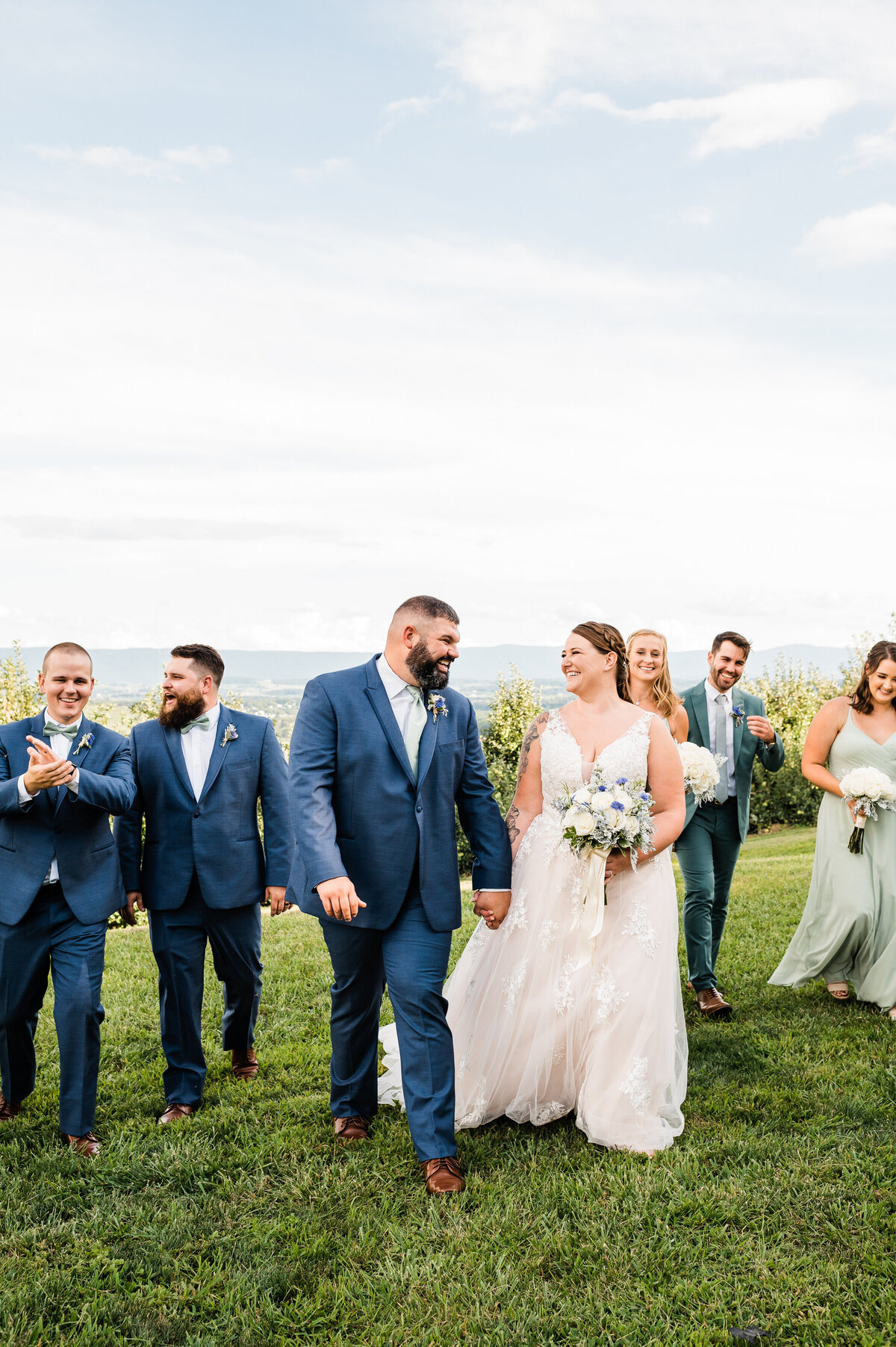 bridal party walking behind the bride and groom on the lawn of the Shenandoah wedding venue at showalter's orchard