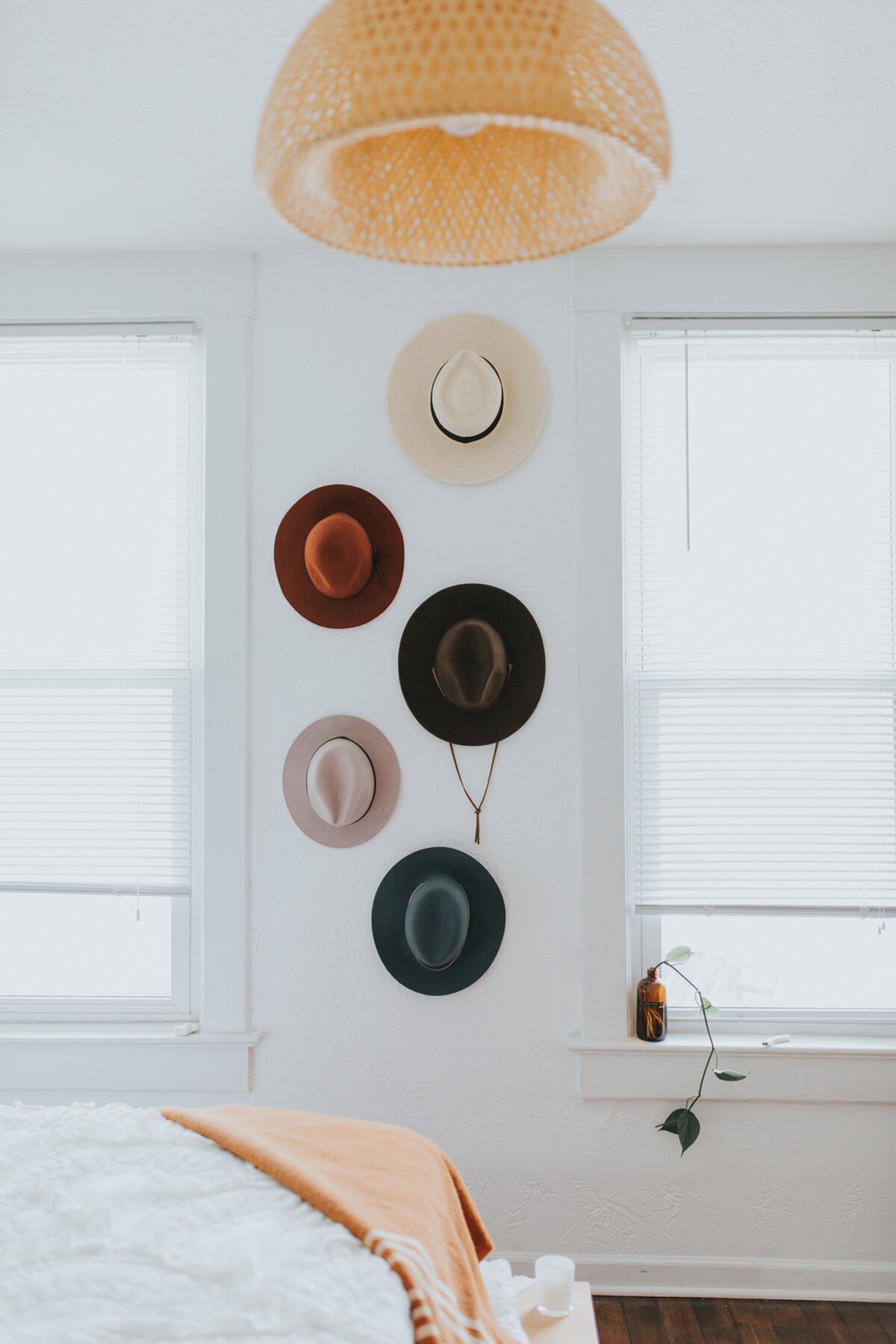 stylish-bedroom-interior-with-wall-mounted-hats-and-wicker-lamp