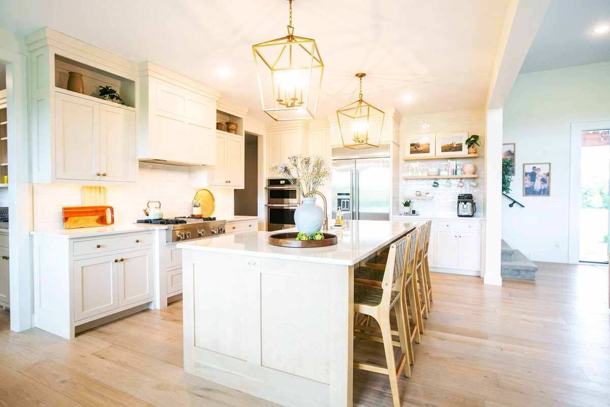 Open kitchen with white cabinets, large island, and quartz countertops in an Otsego custom home