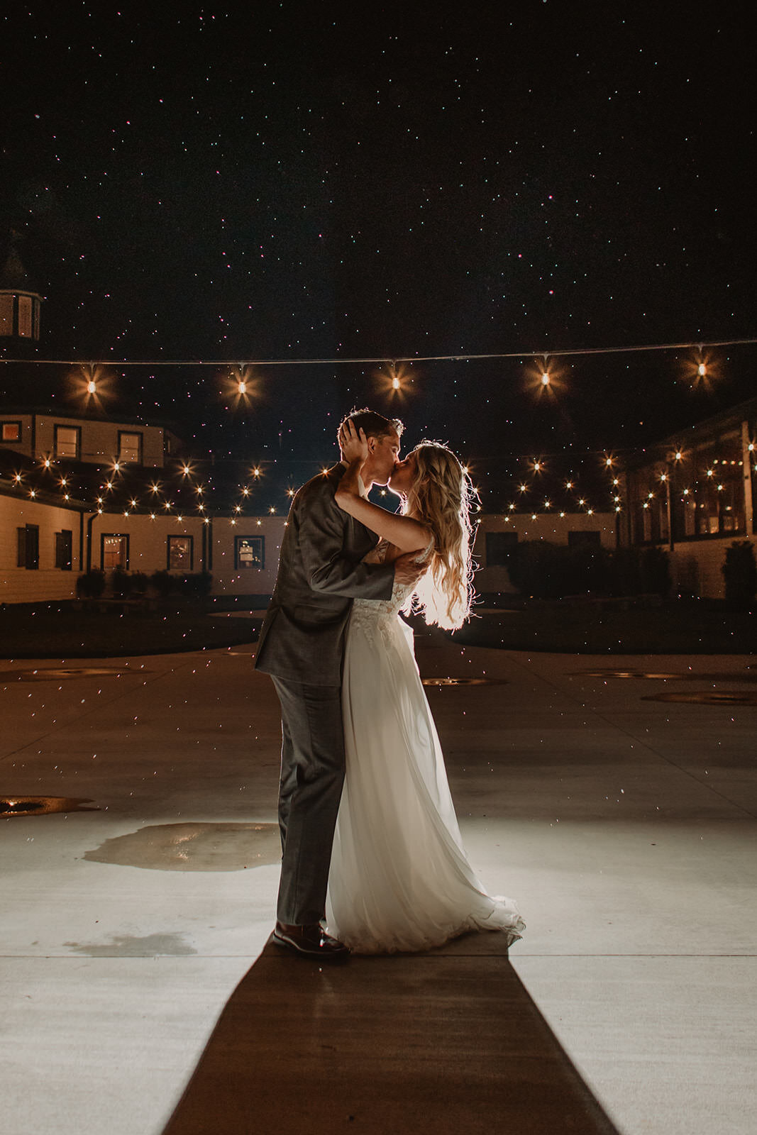 A newlywed couple kissing as they dance under the stars