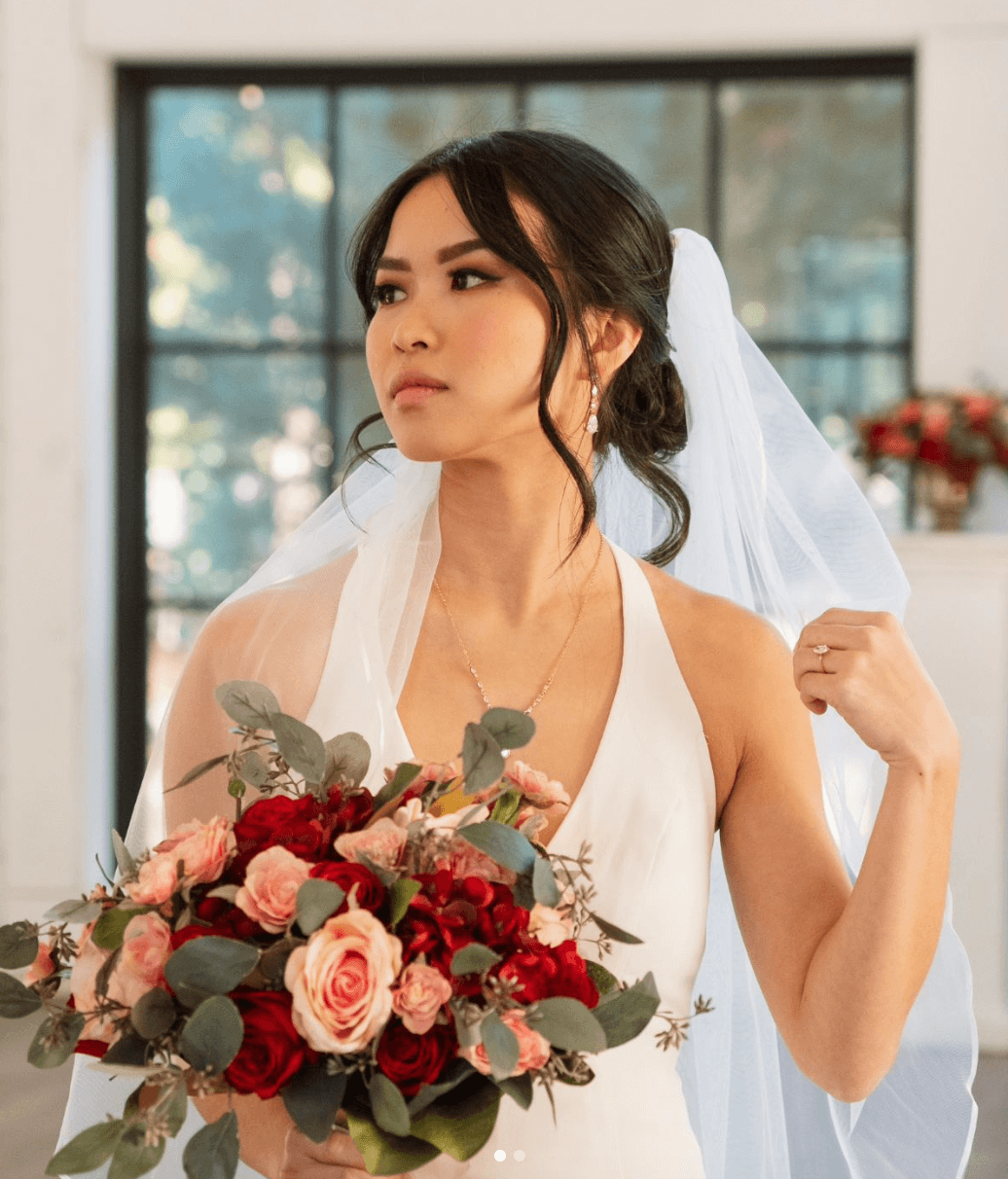 Bride in white dress with romantic low bun, veil, and soft front layers styled by an Austin wedding hairdresser for wedding day hair and makeup