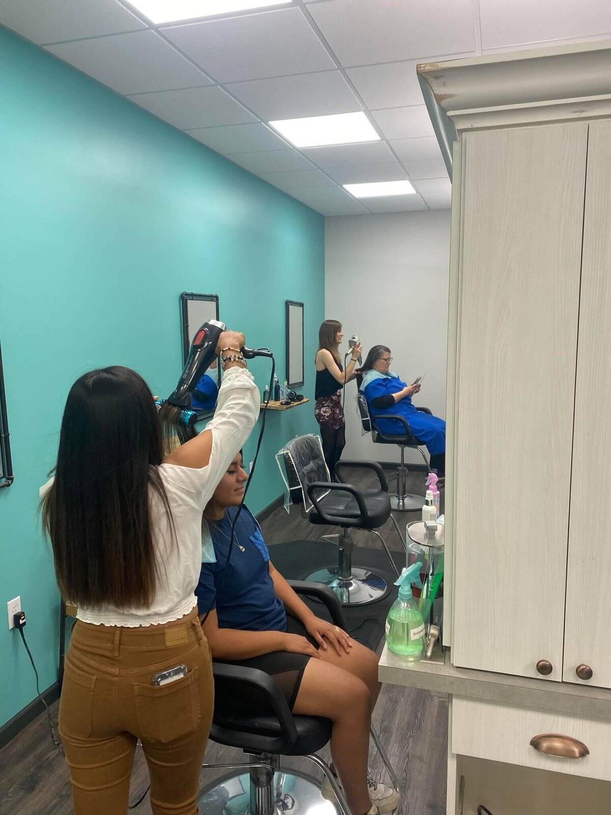 Hairstylists working on clients in a bright, modern salon, showcasing the professional and bustling environment at 212 Salon, Spa, & Barbershop.