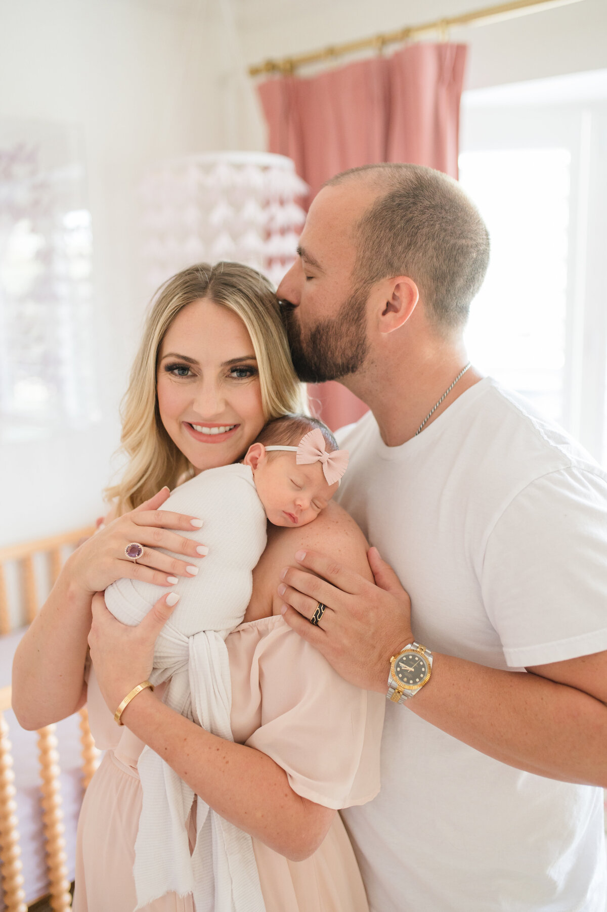 dad kissing mom on head who is holding baby girl