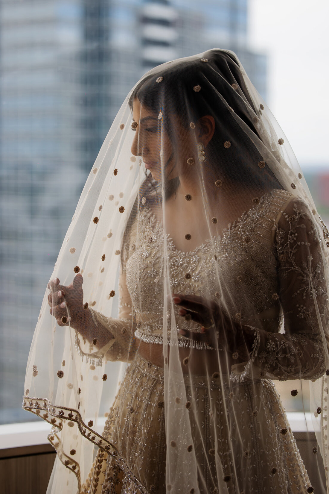 Bride in wedding gown and veil looking out the window.