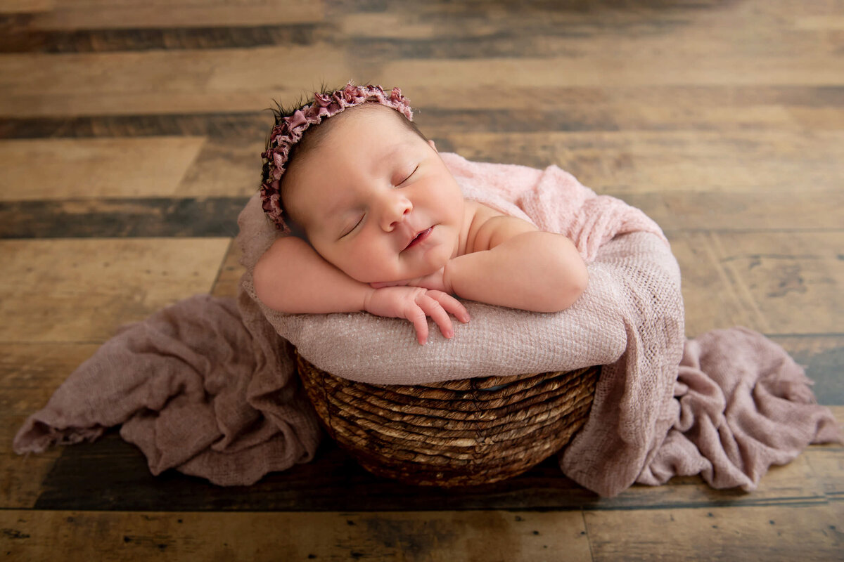 newborn girl in a basket with a pink blanket on her for her newborn photography session in Burlington, Ontario