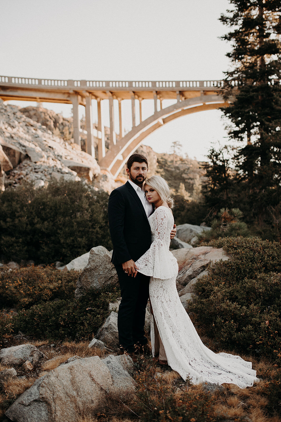 bride and groom embracing each other under a stunning bridge
