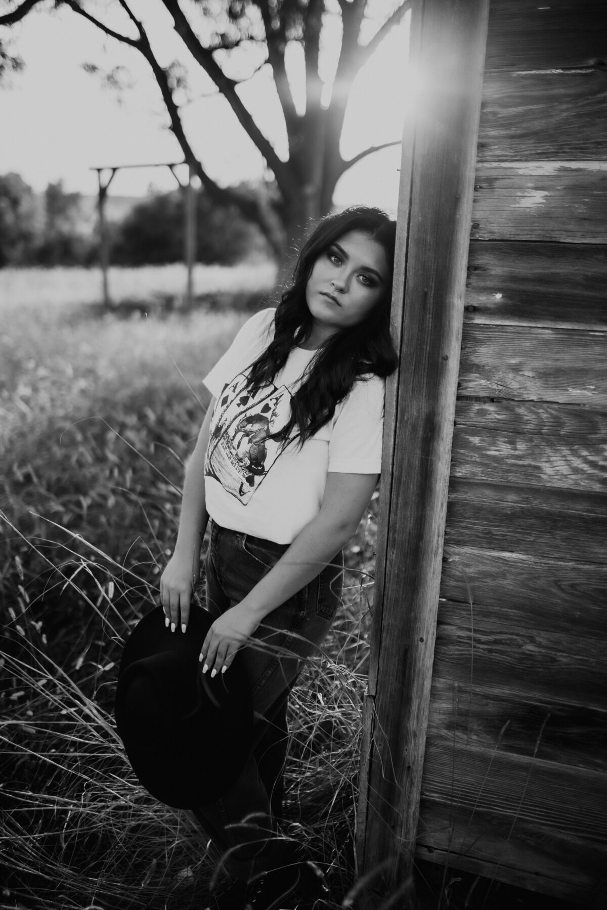 BLACK AND WHITE  SENIOR STANDING AGAINST BARN