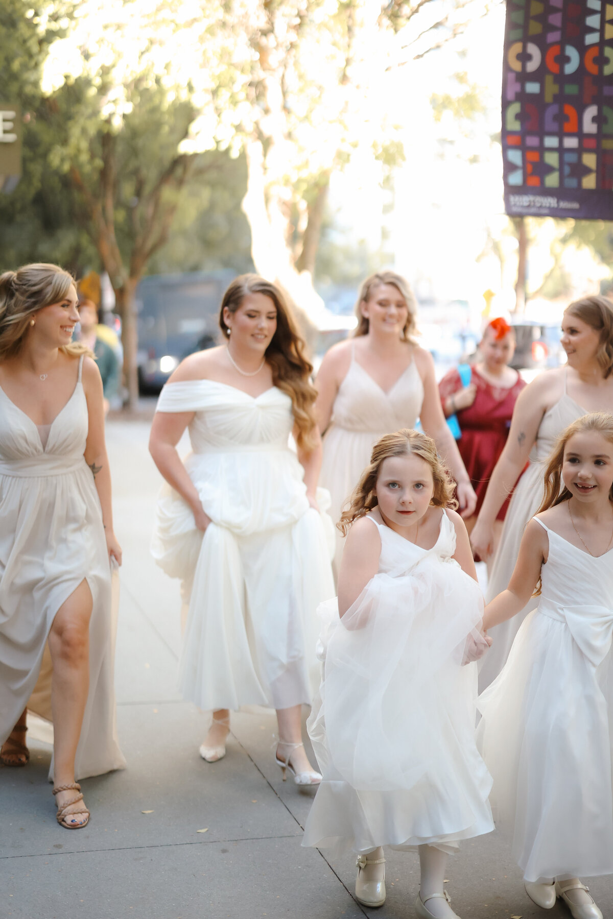 Bride surrounded by her bridesmaids as they help her get ready for the wedding, sharing laughs and joyful moments in a softly lit room.