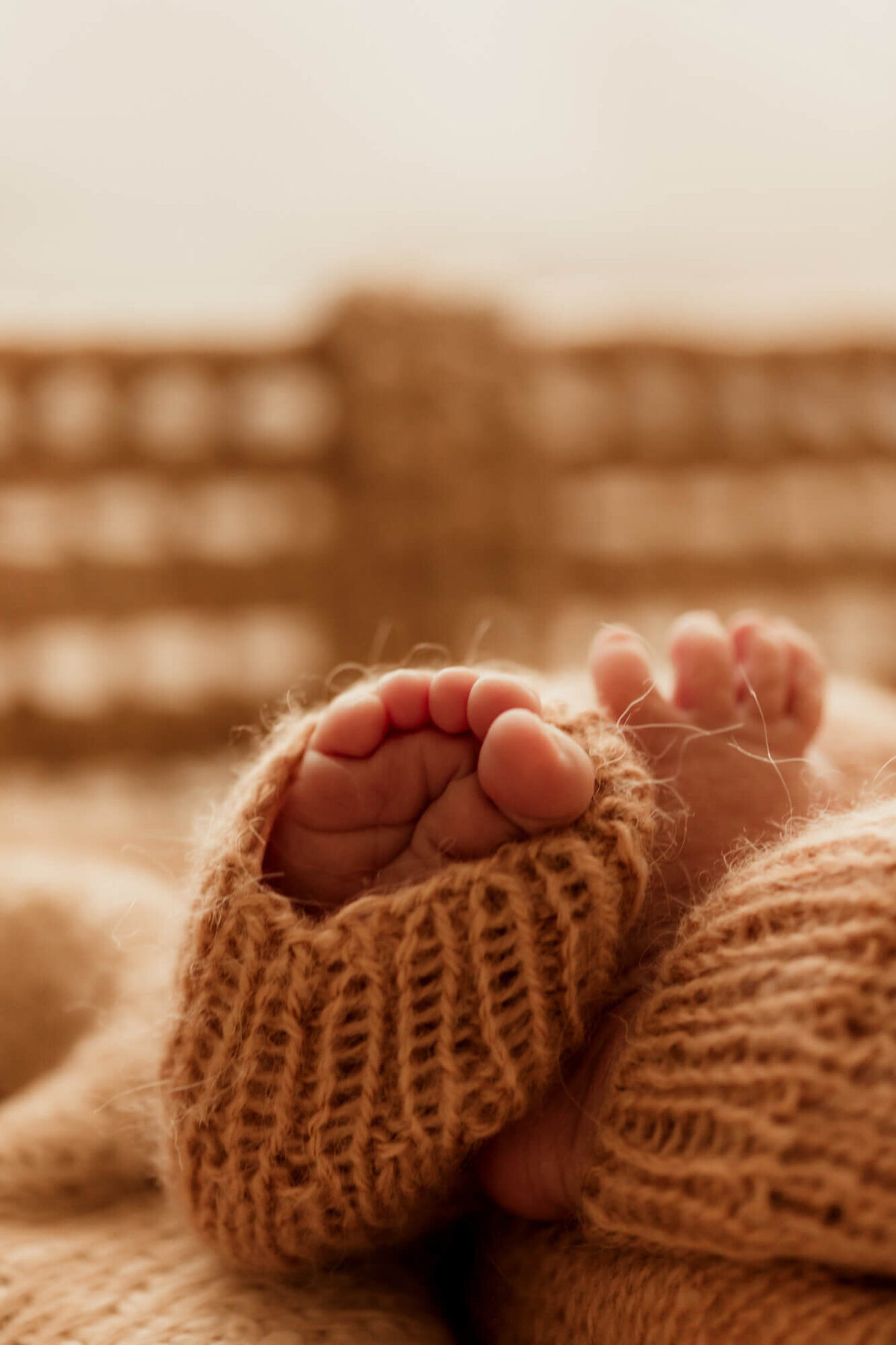 Baby boy's toes covered by a brown knitted romper.