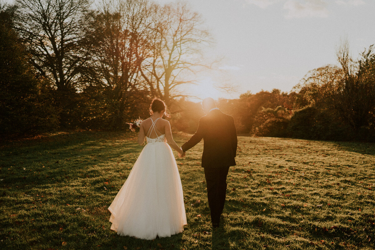 bride and groom walking toward the sunset