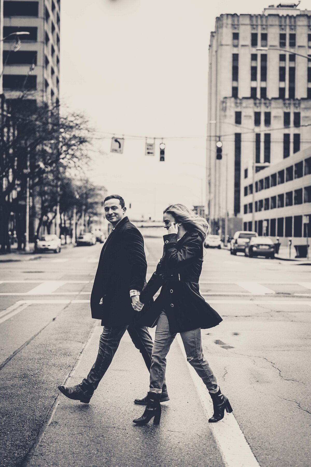 Step into the timeless charm of Justine and Jack's engagement shoot captured in striking black and white as they walk hand-in-hand across a bustling downtown Dayton street. This classic photograph not only symbolizes their journey together but also embraces the cinematic quality of urban life. The simplicity of the black and white filter enhances the emotional connection between the couple, making this a captivating snapshot of their love set against the backdrop of city life. Ideal for couples inspired by the elegance of vintage photography and the dynamic energy of urban settings.