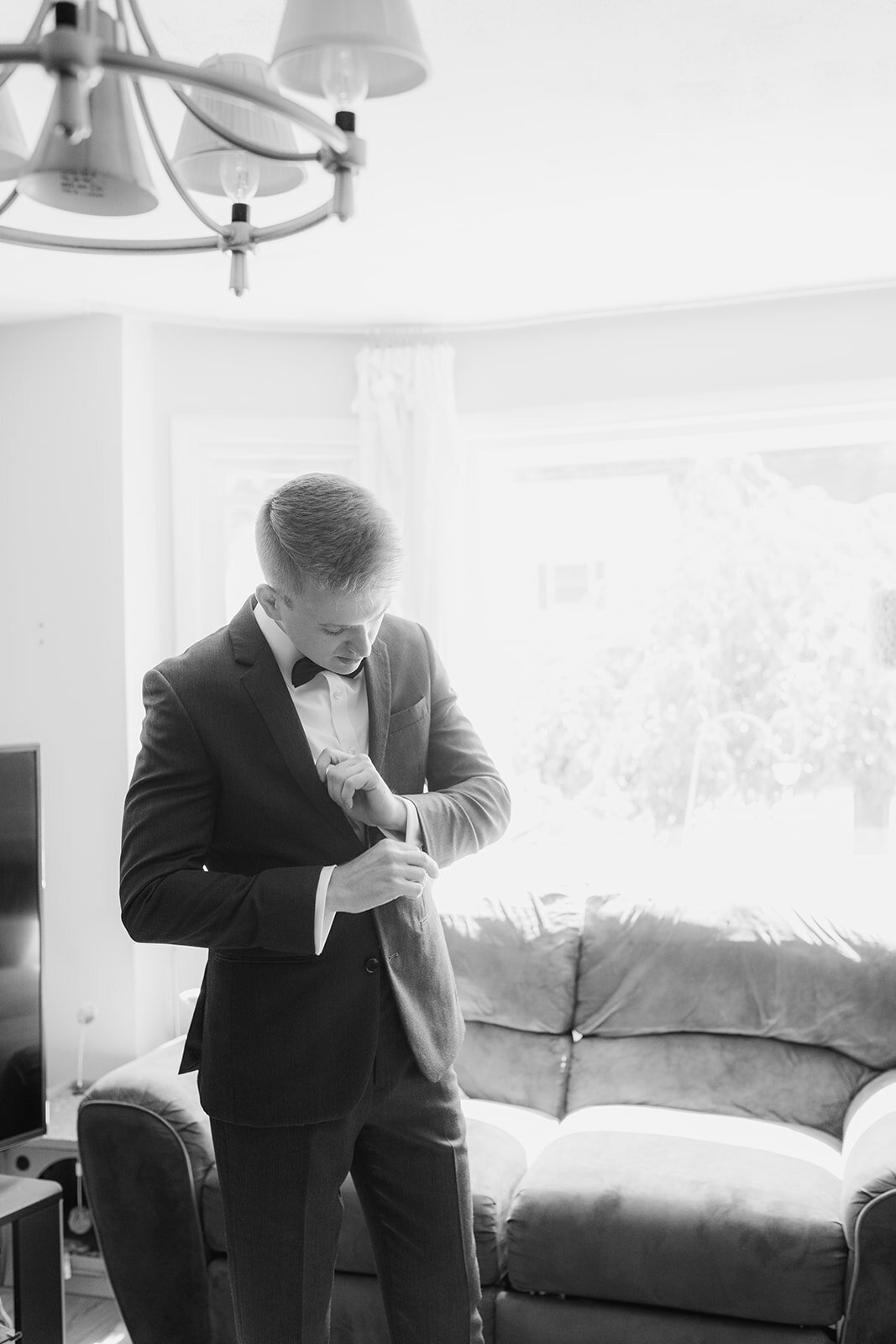 groom adjusts his cufflinks while getting ready for wedding at the grandview