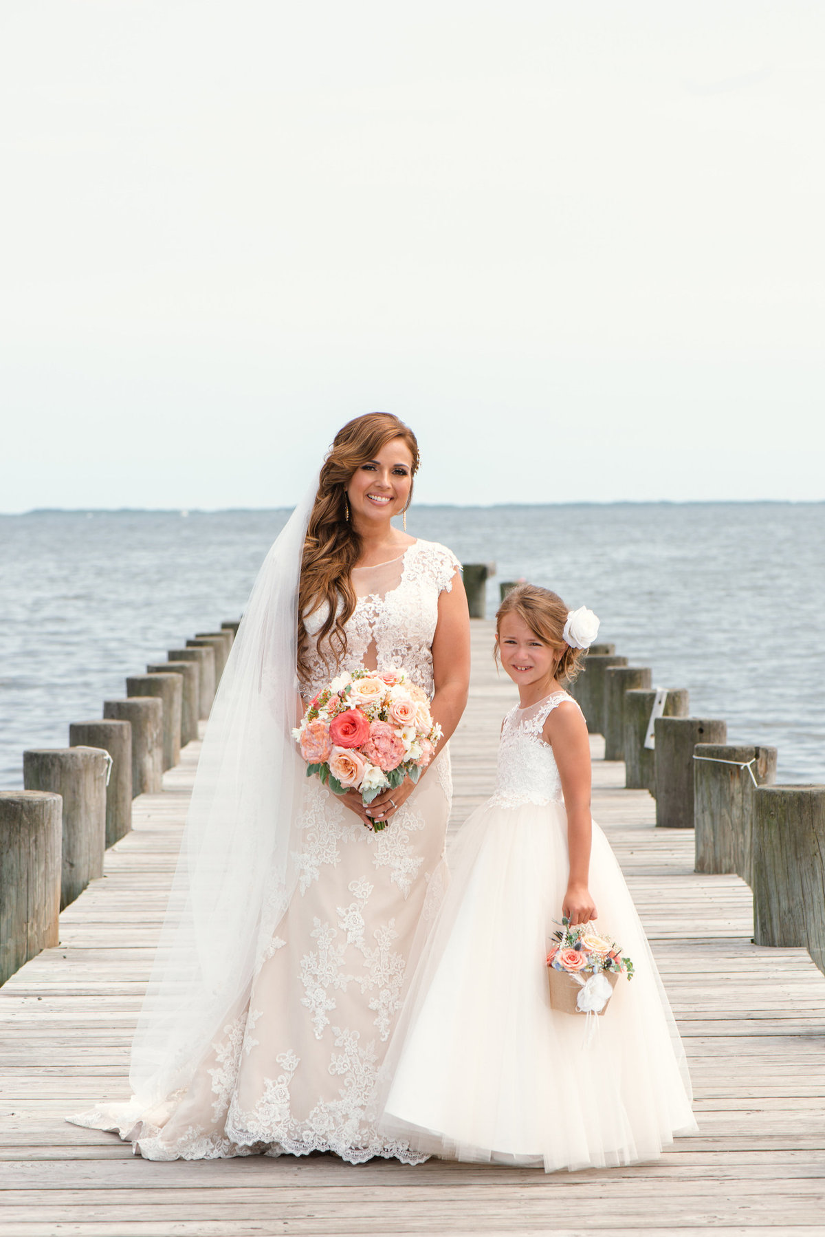 photo of bride with flower girl on the dock for wedding reception at Lombardi's on the Bay