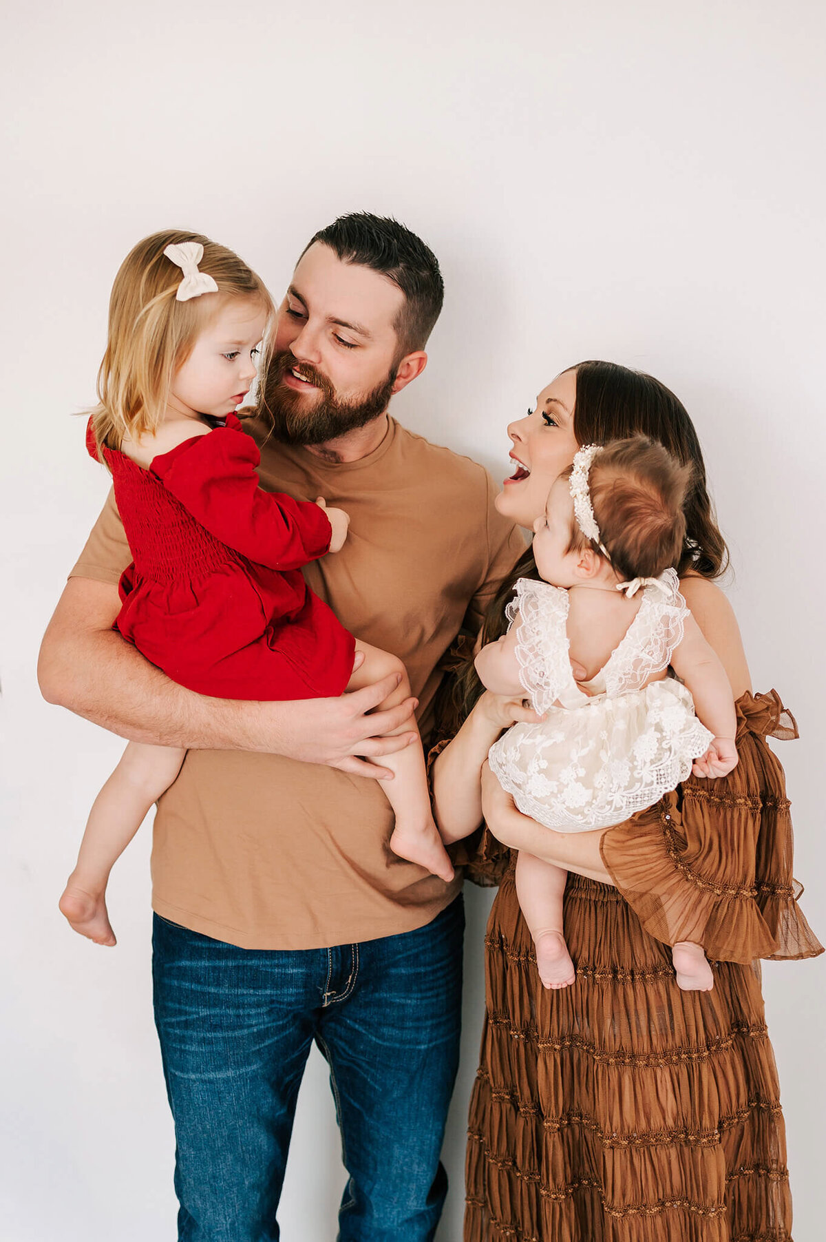 family smiling to each other while holding daughters during Branson MO family photography session