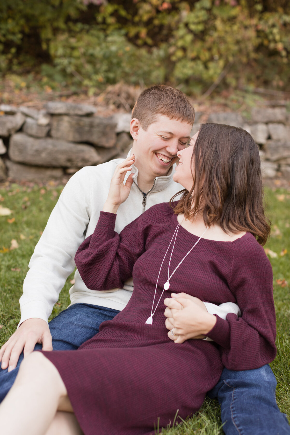 Engaged couple seated with bride in his lap smiling at each other