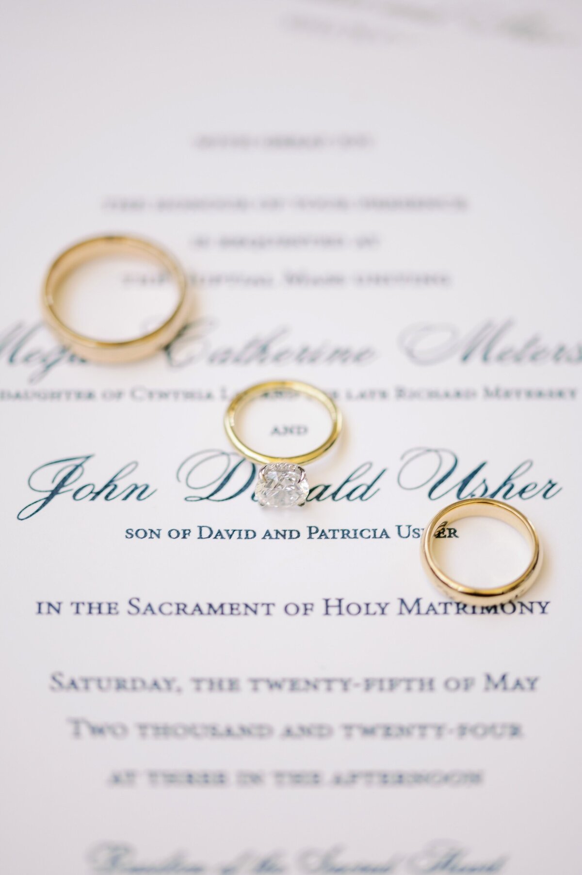 close up of wedding rings laying on top of wedding stationery