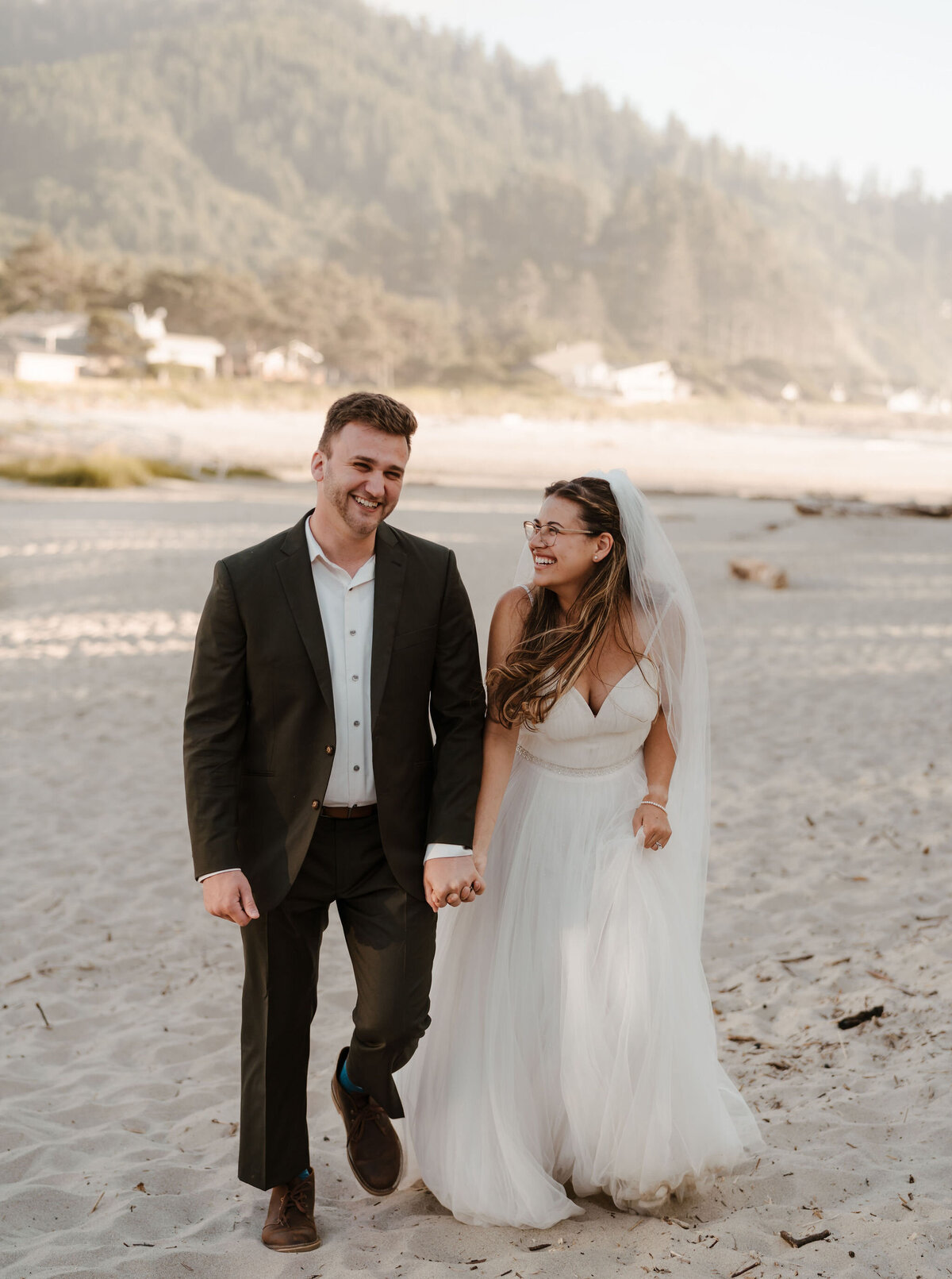 a bride and groom walking on the beach