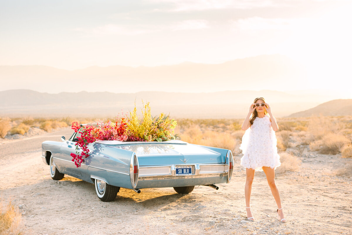 bride standing in california desert with vintage blue car