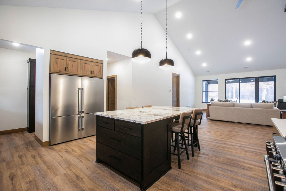 Open kitchen with dark cabinets, large island, and quartz countertops in an Elk River custom home