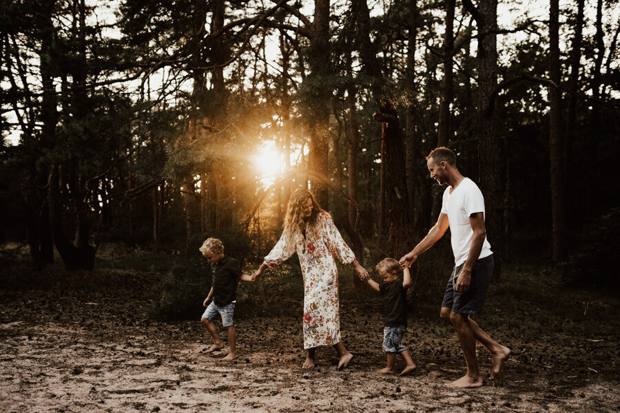 familj håller hand och går tillsammans längs med skogen i halmstad