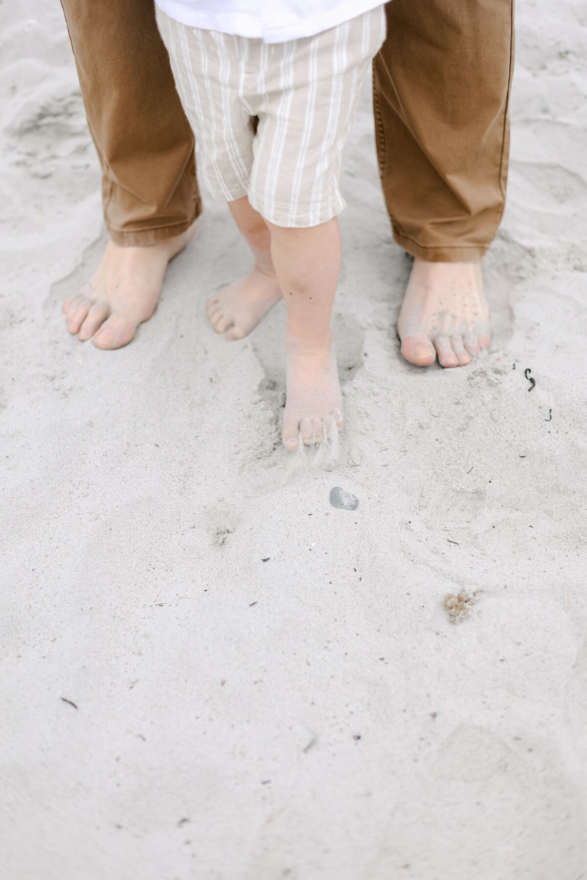 toddler boy and father with their toes in the sand during a NH Family Photographer beach session in Rye NH