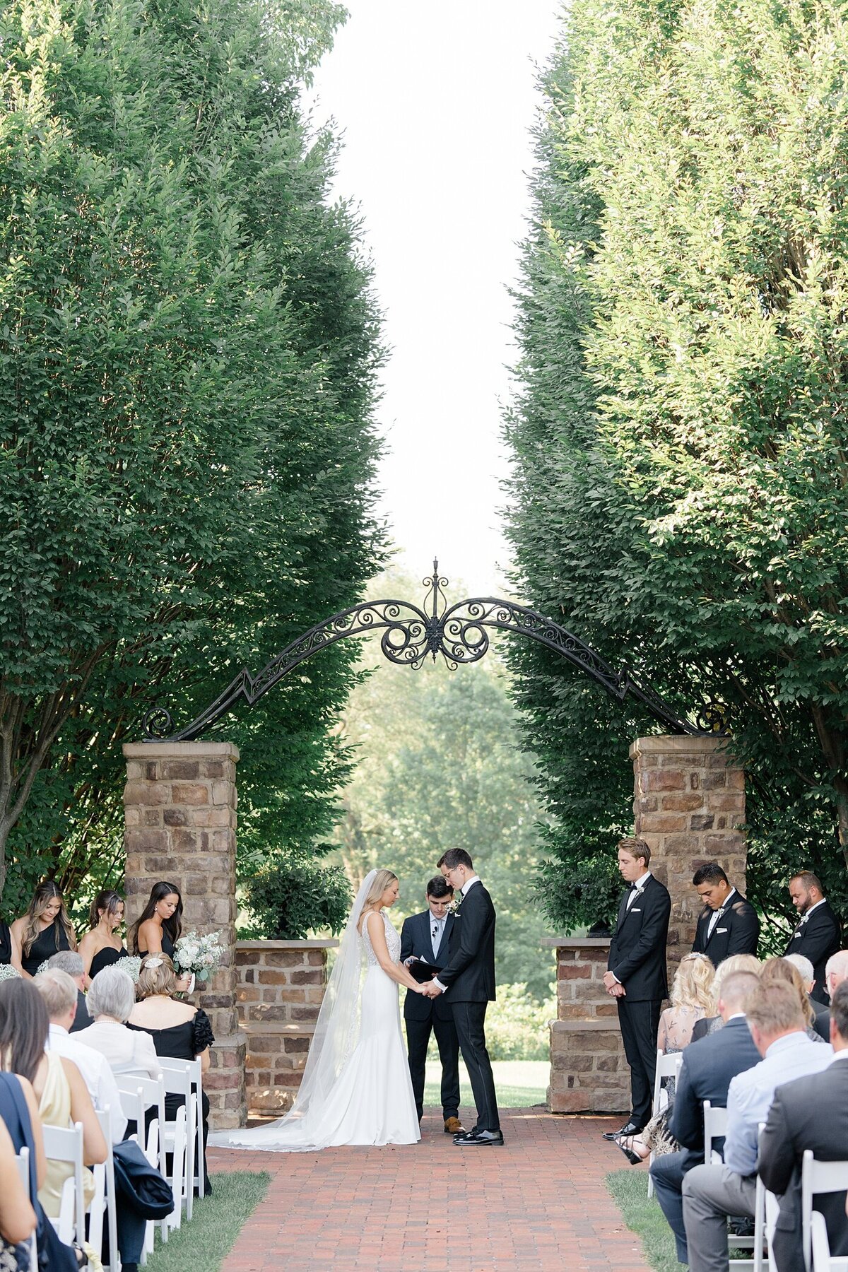 outdoor wedding ceremony at Pinnacle Golf Club wedding venue with couple holding hands and bowing their heads in prayer