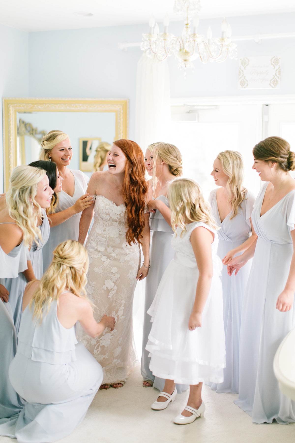 bride laughing with bridesmaids wearing sky blue dresses