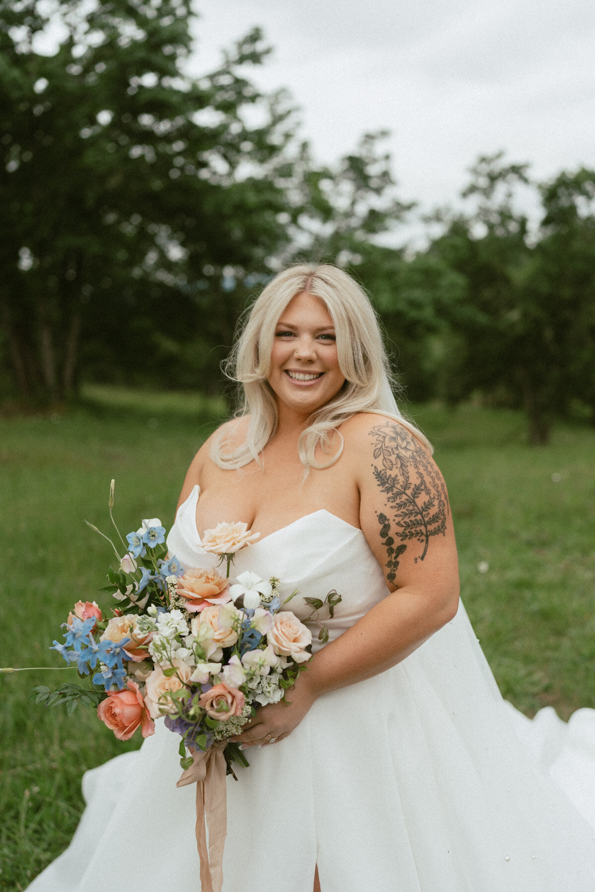 A bride standing outdoors with flowers, representing bridal makeup done by Looks with Libby.