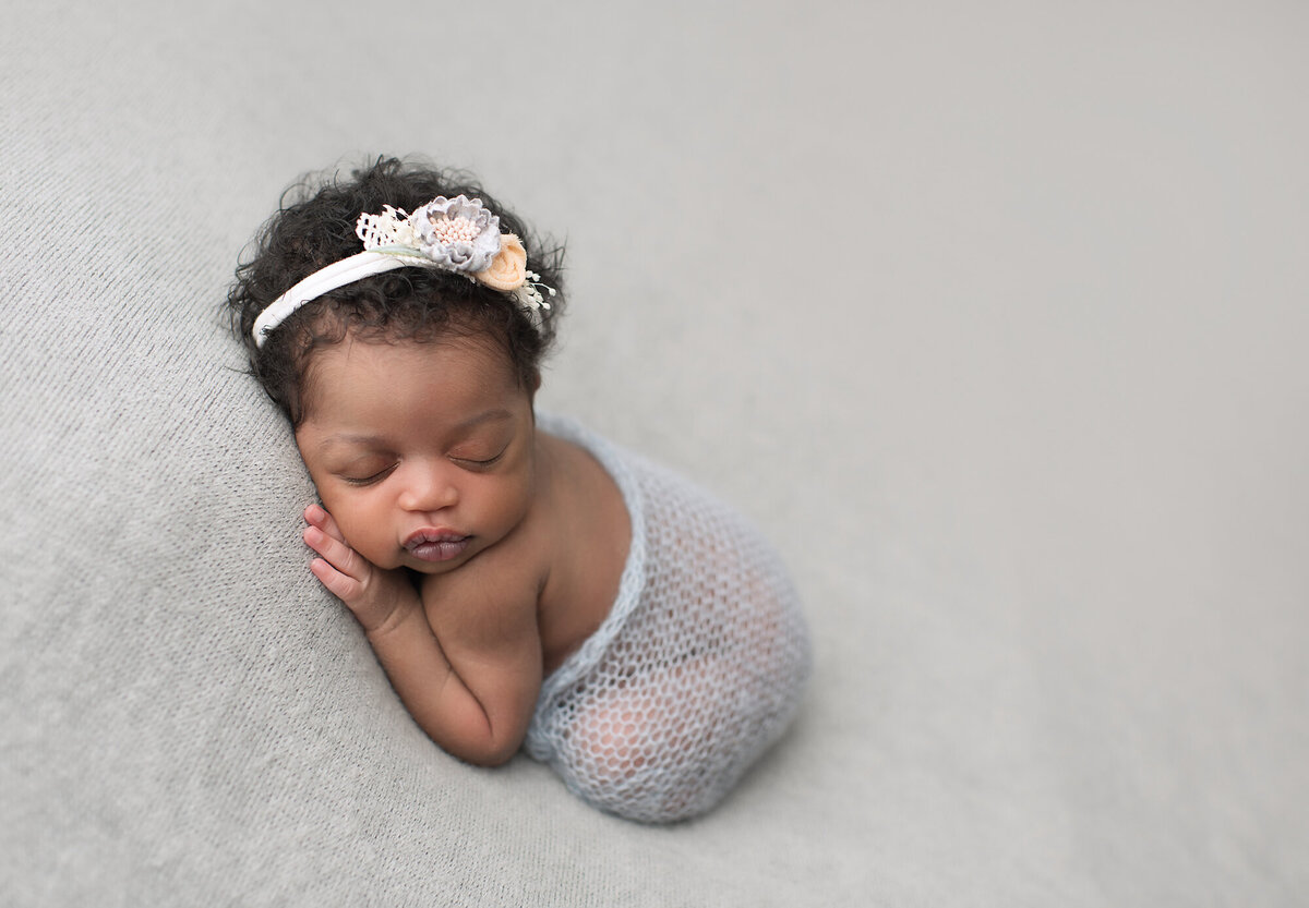 baby posed with headband and light gray background colors