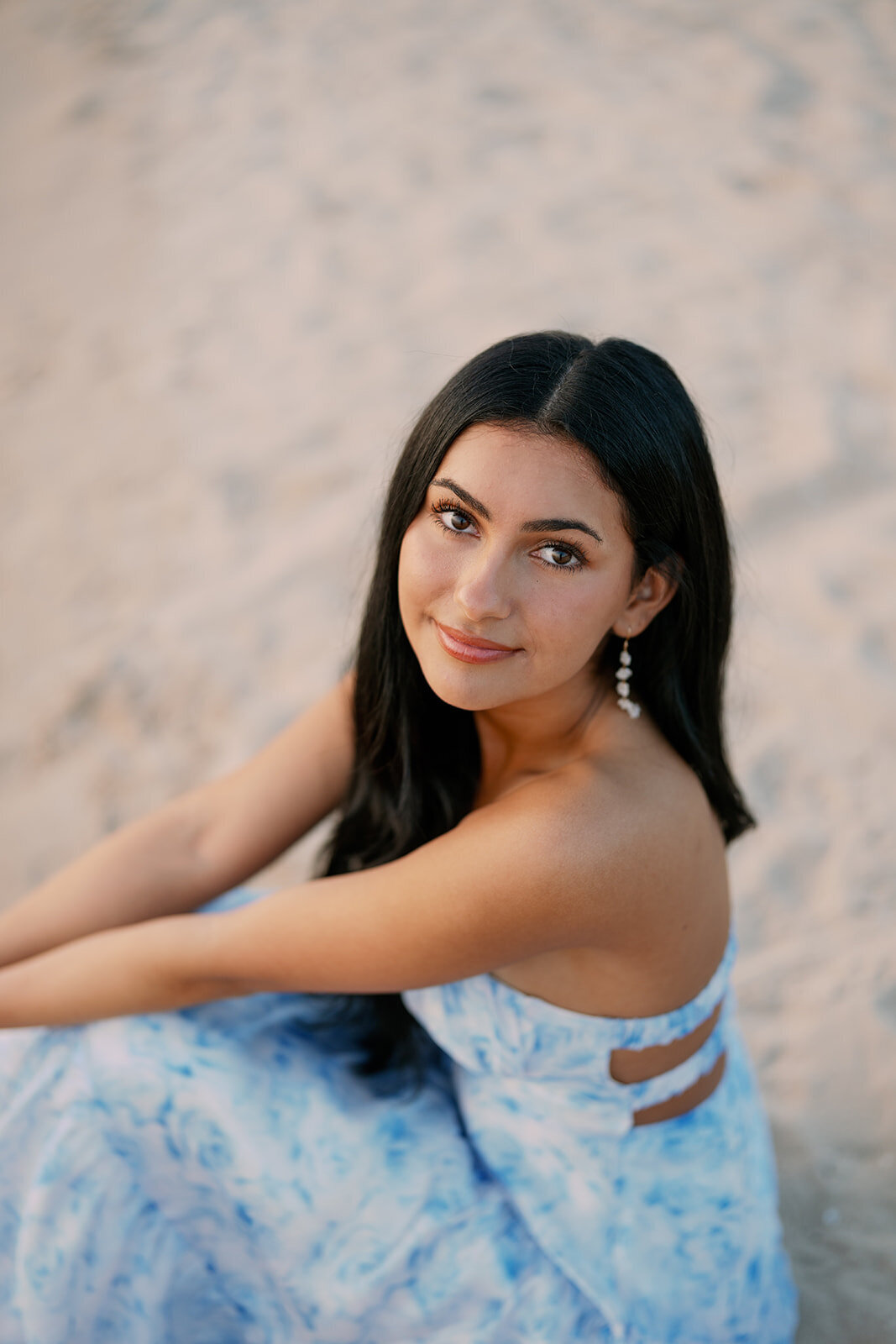 Teen girl posing on the beach in a blue floral dress during her South Haven Michigan senior portraits.