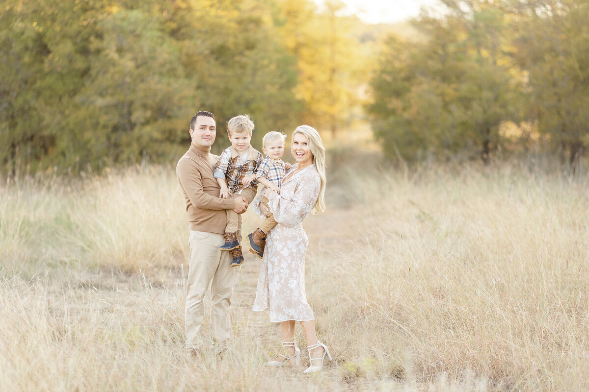 A beautiful sunset photo of a Dallas family standing by a grassy path posing for their family pictures.