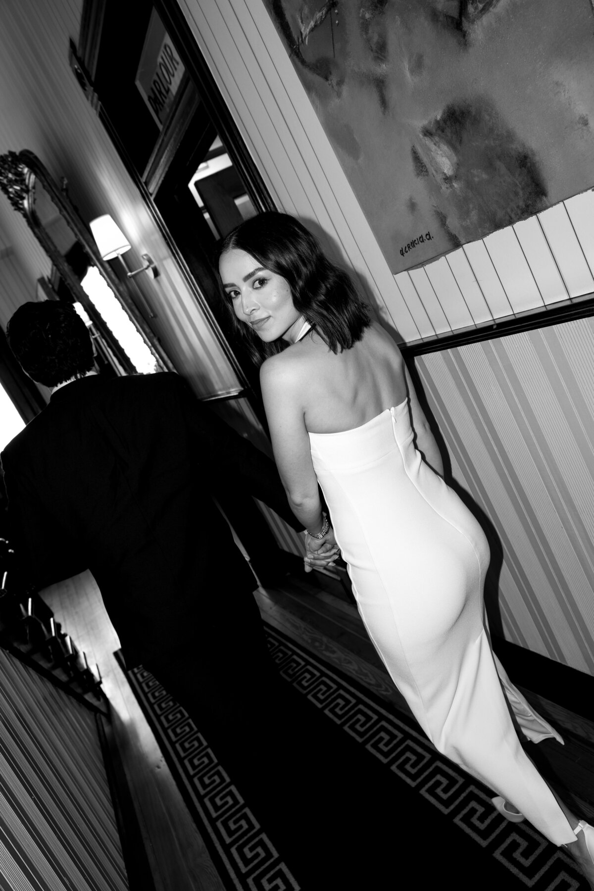 bride walking hand in hand with groom and looking back at the camera