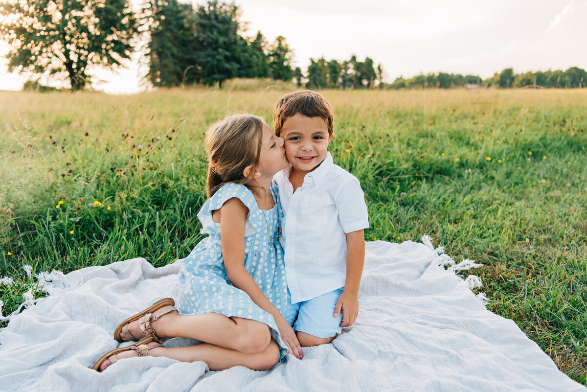 Sister kissing little brother on the cheek