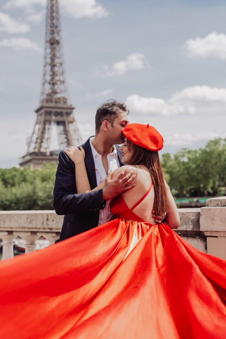 Romantic kiss at Eiffel Tower, red flying dress with matching beret, Paris couple photography session