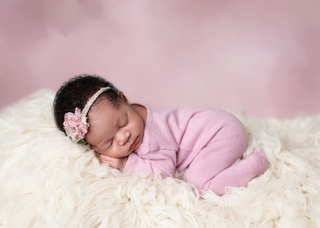 Sleeping newborn girl in pink outfit on cream flokati – studio portrait by Misty Dawn Photography, Birmingham AL
