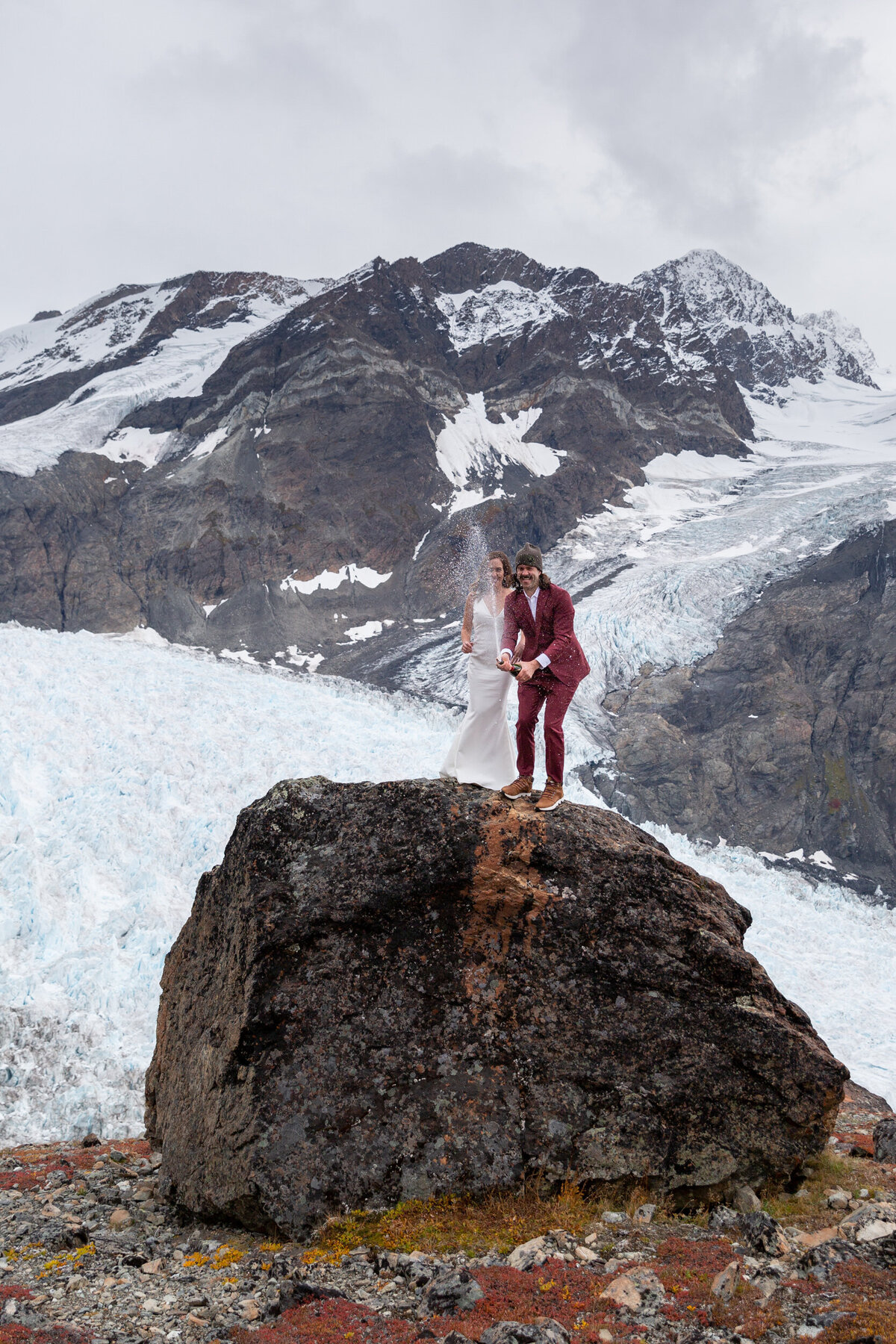 A bride and groom spray champagne towards their Alaska elopement photographer.