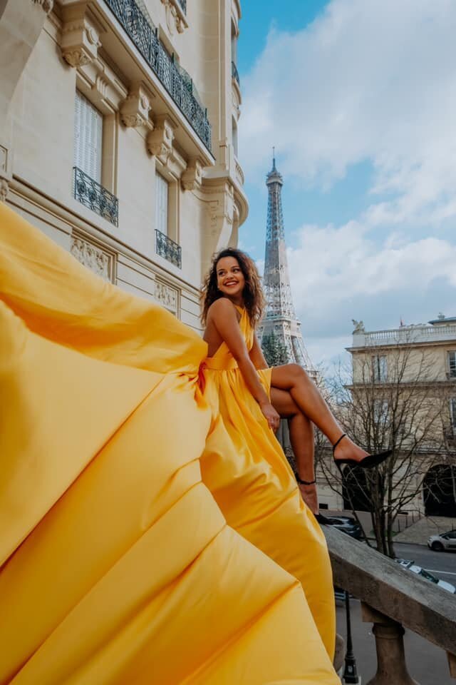 Women wearing a yellow flying dress in front of the eiffel tower in paris