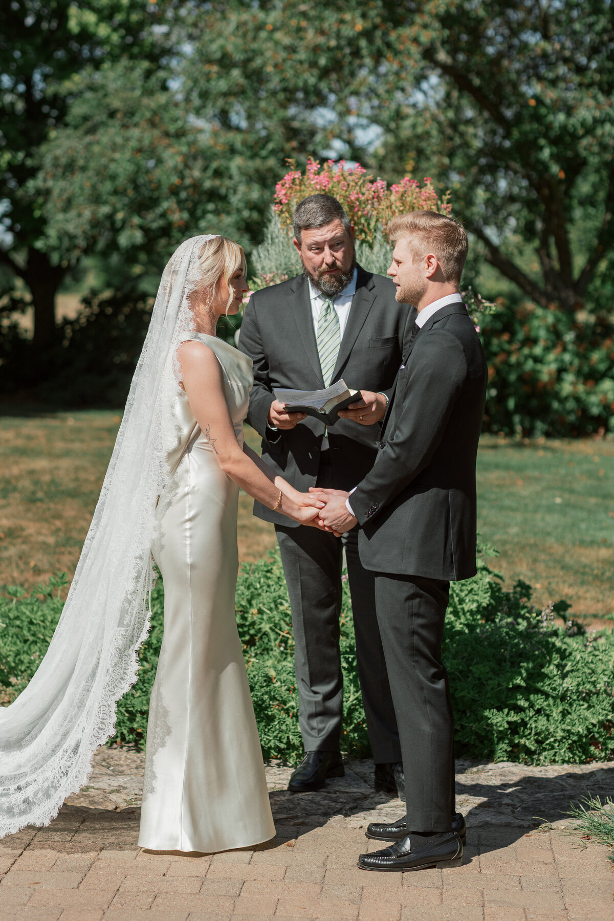 Bride and groom hold hands during intimate Dayton ceremony, photographed by Philly-based wedding expert.