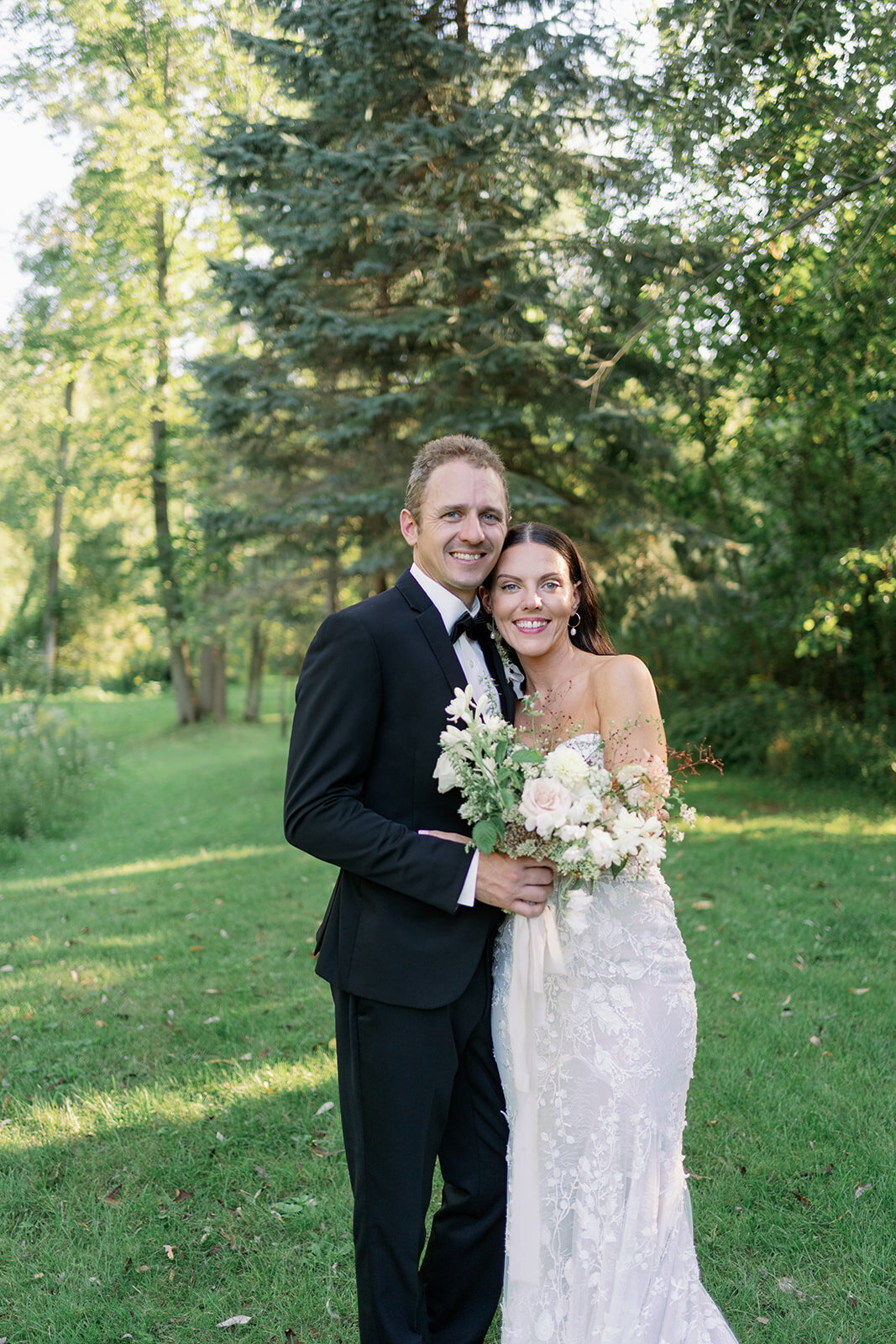 Bride and groom standing in the garden at Glasshouse Community in Ottawa County during their summer greenhouse wedding, photographed by Michigan wedding photographer.
