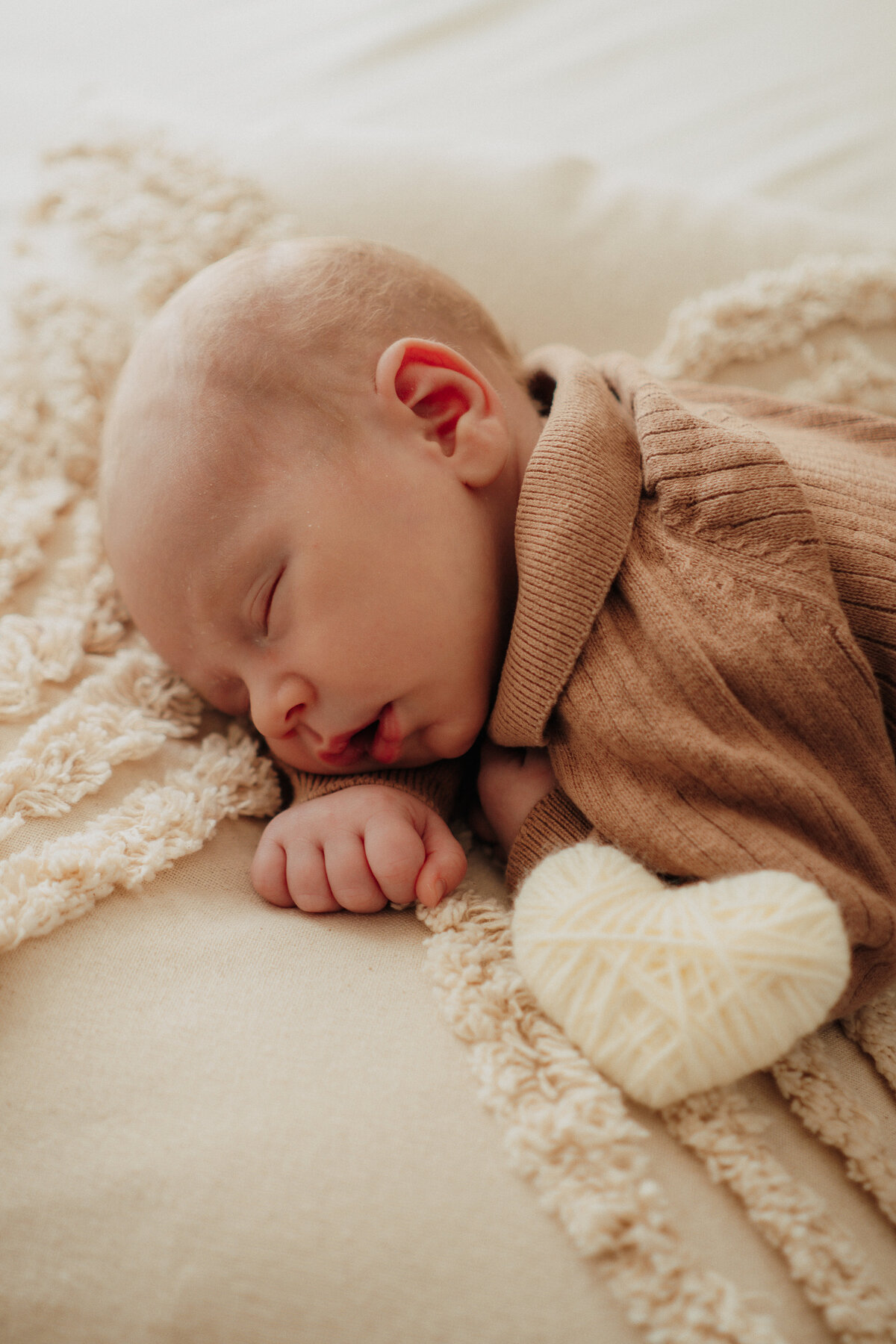 Papa hält Baby im Arm, Hand umfasst das Köpfchen und er gebt einen sanften Kuss