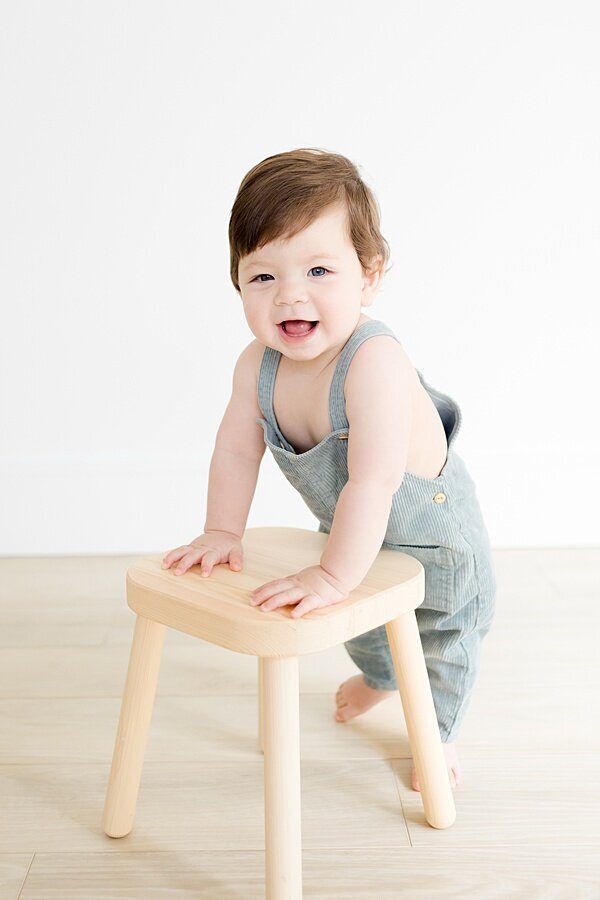 Toddler holding onto stool at 1 year milestone photo session