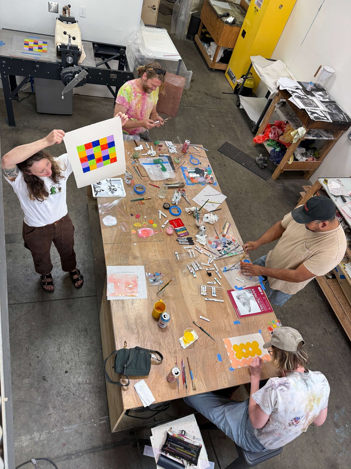 Wide view of the Moonlight Press studio with participants working on their monoprints, showing colorful works in progress and collaborative energy.